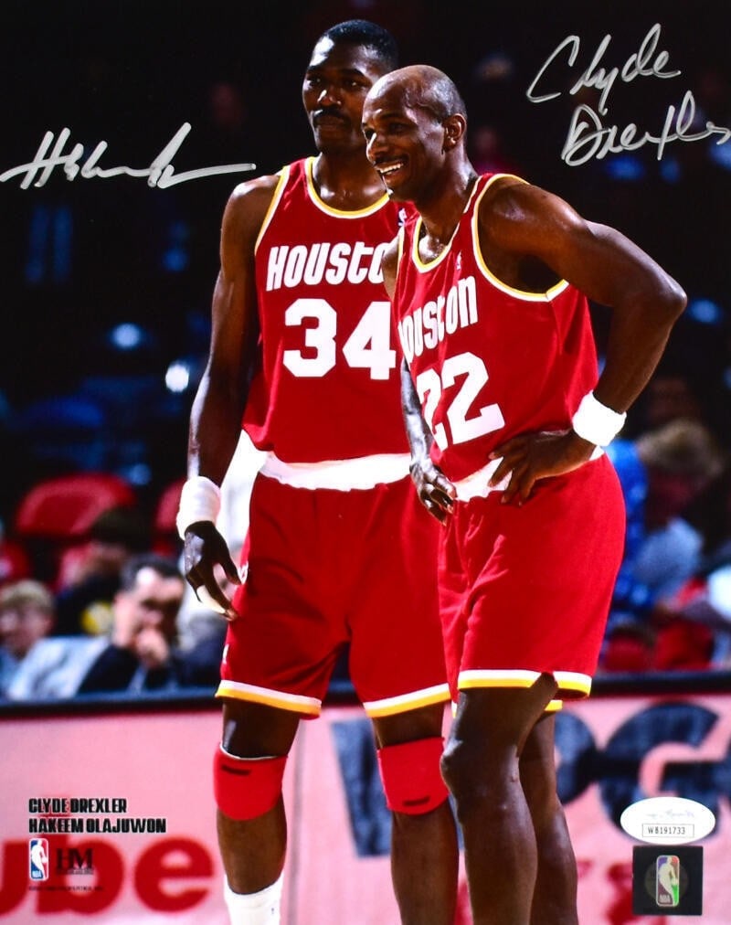 Houston Rockets 8x10 Photo Signed by Clyde Drexler and Hakeem Olajuwon JSA Authenticated: Houston Rockets 8x10 Photo Signed by Clyde Drexler and Hakeem Olajuwon JSA Authenticated This is an original 8x10 photo featuring Clyde Drexler and Hakeem Olajuwon of the Houston Rockets, autographed 