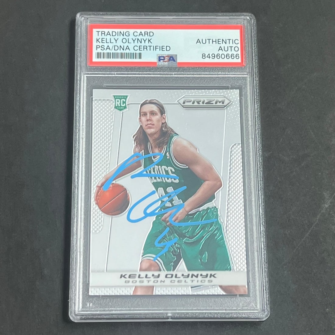Kelly Olynyk Rookie Prizm Card PSA DNA Authenticated Autograph #272: Kelly Olynyk Rookie Prizm Card PSA DNA Authenticated Autograph #272 This is a 2013-14 Panini Prizm #272 rookie card featuring Kelly Olynyk, who played for the Boston Celtics. The card is signed by Kel