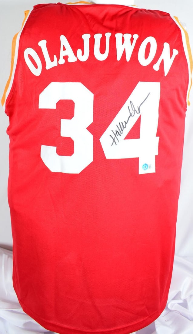 Hakeem Olajuwon signed Houston Rockets red pro style jersey Beckett hologram: Hakeem Olajuwon signed Houston Rockets red pro style jersey Beckett hologram This red pro style jersey features the autograph of basketball legend Hakeem Olajuwon. The jersey represents the Houston Ro