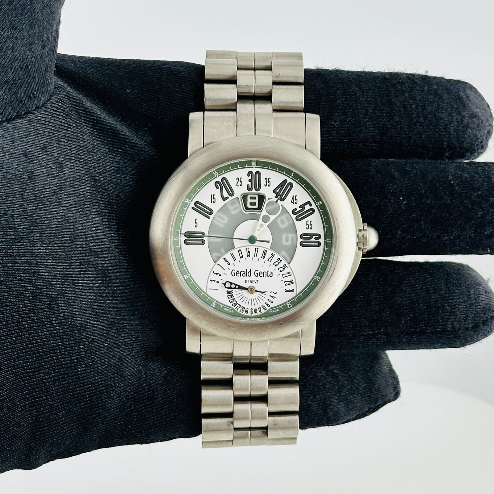Gerald Genta Arena Bi Retro Titanium Bracelet White Arabic Dial BSP.Y.80: Gerald Genta Arena Bi Retro Titanium Bracelet White Arabic Dial BSP.Y.80 This Gerald Genta Arena Bi-Retro watch features a white dial with Arabic numerals, complemented by a smooth bezel and a titaniu
