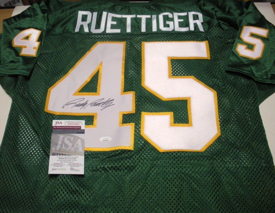 Rudy Ruettiger Signed Notre Dame Wilson Jersey with JSA COA: Rudy Ruettiger Signed Notre Dame Wilson Jersey with JSA COA This officially licensed Wilson jersey, signed by Rudy Ruettiger, is a must-have for any Notre Dame Irish fan. The jersey showcases the spir