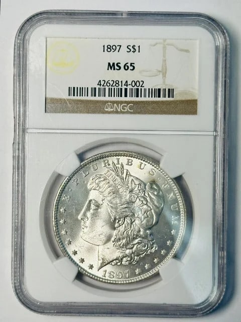 NGC MS 65 1897 Morgan Silver Dollar: NGC MS 65 1897 Morgan Silver Dollar This 1897 Morgan Silver Dollar has been graded MS 65 by NGC, indicating a high level of preservation. Composed of silver, this pre-owned coin originates from the US
