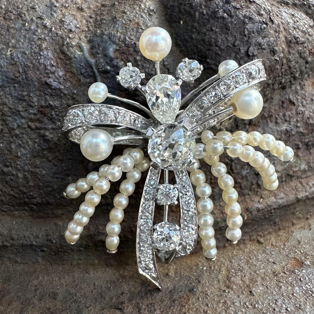 Antique 13-14k White Gold Diamond Pearl Ribbon Brooch Pin: Antique 13-14k White Gold Diamond Pearl Ribbon Brooch Pin This antique brooch features an elegant bow ribbon design crafted in solid 13-14k white gold. It is adorned with a total of 37 natural diamond