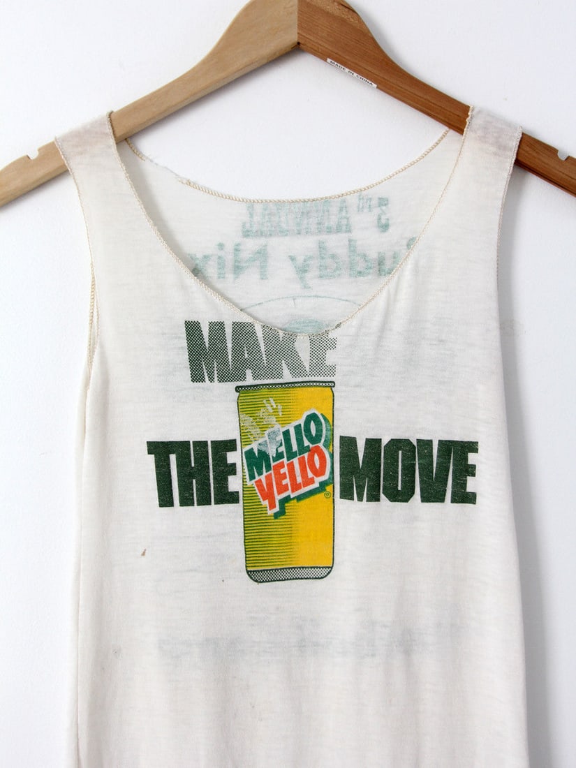 1980s Mello Yello Buddy Nix Football Tank Top Vintage Tee: 1980s Mello Yello Buddy Nix Football Tank Top Vintage Tee This vintage 1980s Mello Yello tank top is a unique piece cut from an extra-thin t-shirt. The front showcases a vibrant 'Make the Move Mello Y