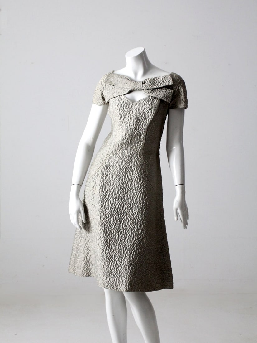 1960s Estevez Vintage Dress with Bow and Sweetheart Neckline: 1960s Estevez Vintage Dress with Bow and Sweetheart Neckline Step back into the elegance of the 1960s with this vintage Estevez dress. Celebrated for its exquisite tailoring and distinctive necklines,