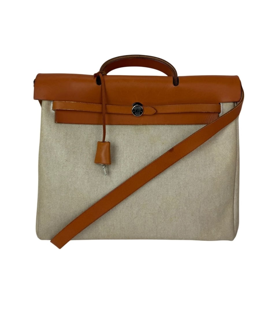 Herbag 39 MM Shoulder Bag in Natural Canvas and Leather by Hermes: Herbag 39 MM Shoulder Bag in Natural Canvas and Leather by Hermes This Hermes Herbag 39 MM shoulder bag features a rectangular silhouette crafted from natural canvas with a matte finish. The bag has b