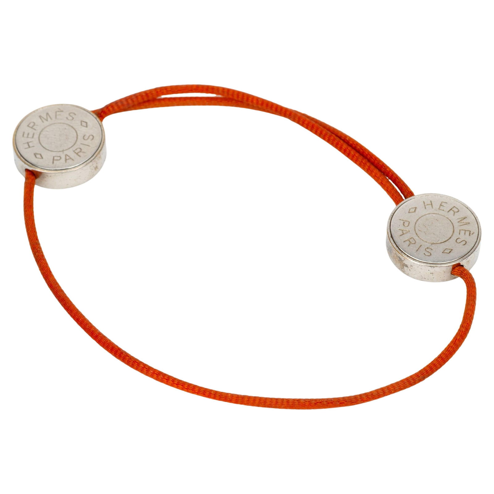 Hermes Clou de Selle orange cord bracelet palladium detail: Hermes Clou de Selle orange cord bracelet palladium detail This Hermes "Clou de Selle" Cord Bracelet features an orange leather adjustable cord accented with a palladium engraved detail. Crafted in 20