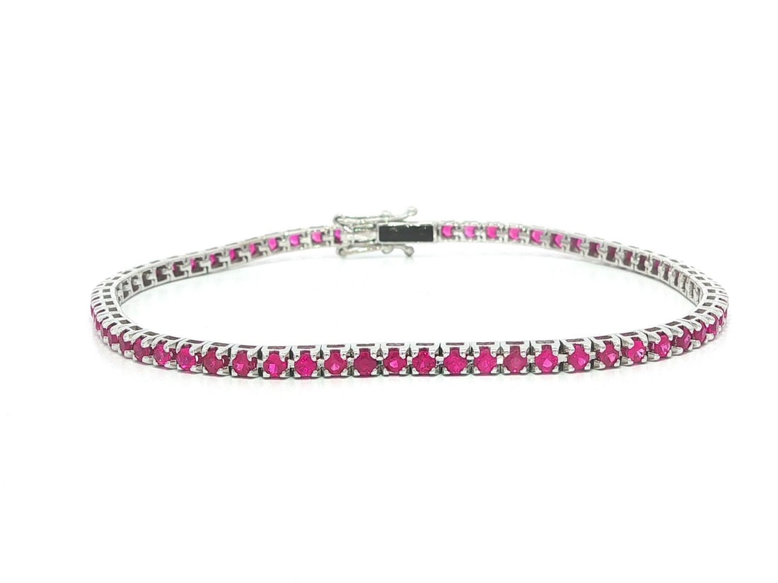 18k White Gold Ruby Tennis Bracelet 2.45ctw 6.5 in: 18k White Gold Ruby Tennis Bracelet 2.45ctw 6.5 in This unbranded tennis bracelet features numerous natural, round brilliant cut rubies with a bright, slightly pinkish red hue. The stones are pave set