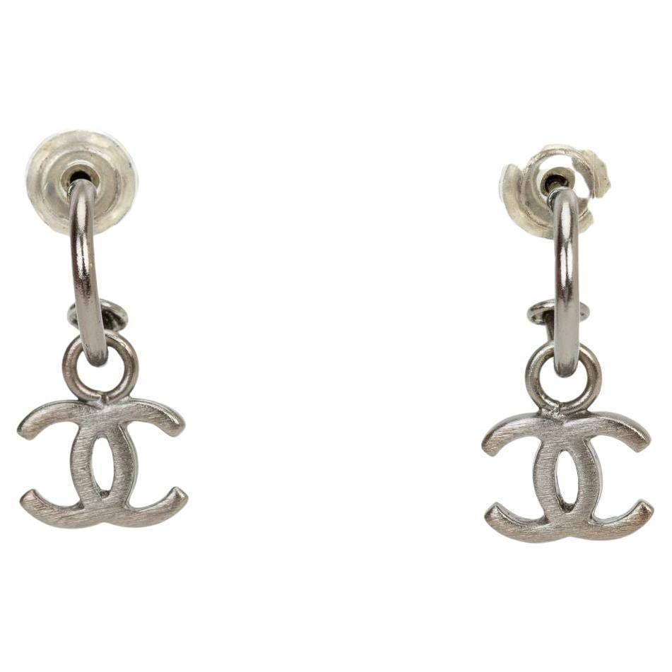Chanel Sterling Silver Hoop Swing CC Dangle Earrings: Chanel Sterling Silver Hoop Swing CC Dangle Earrings These Chanel 80's Door Knocker Earrings showcase a hoop swing design with signature CC dangles, crafted in sterling silver with silver tone hardwar