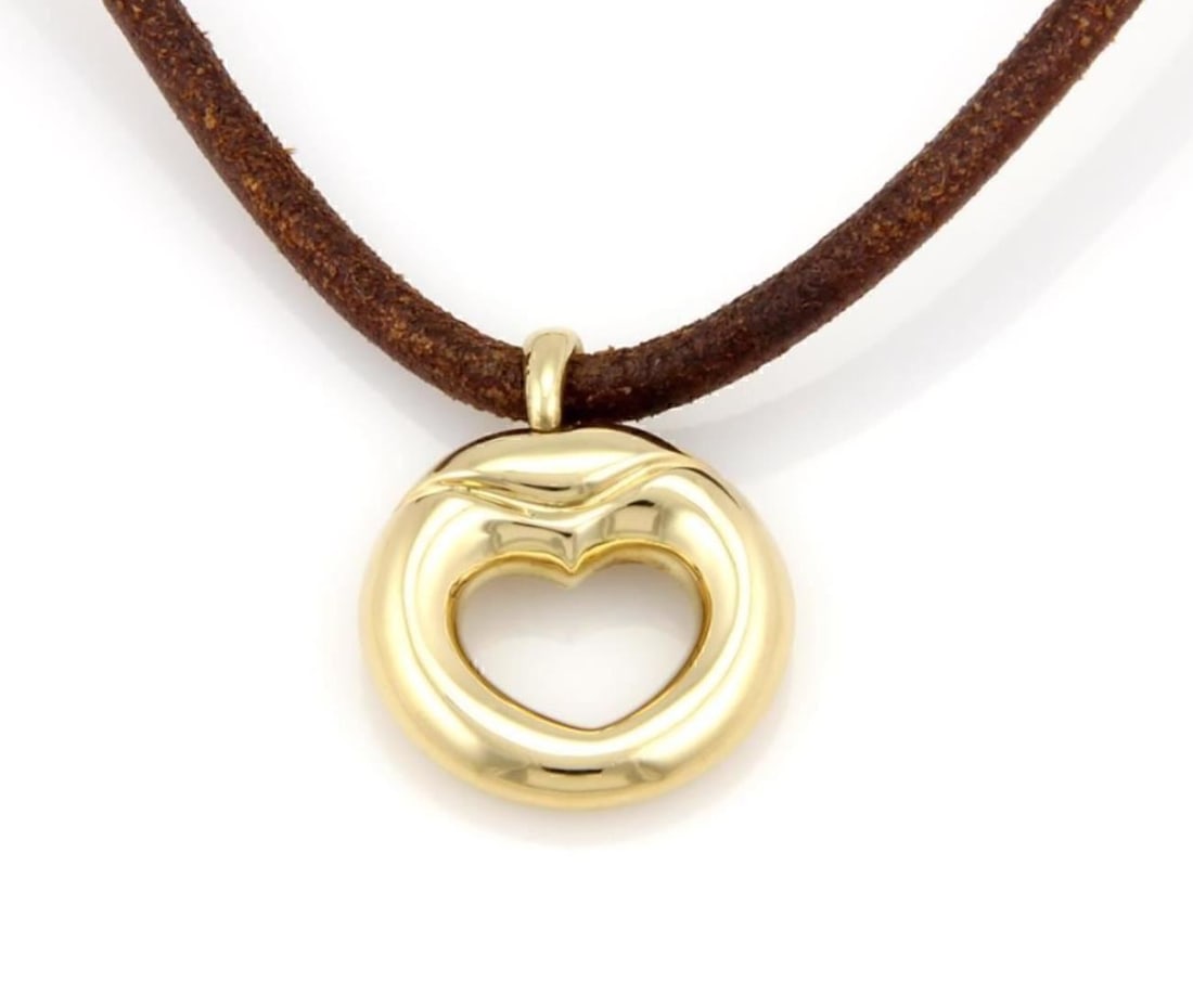 Heart pendant necklace in 18k yellow gold and leather by Movado: Heart pendant necklace in 18k yellow gold and leather by Movado This vintage Movado necklace features a heart-shaped pendant on a leather cord, crafted in 18k yellow gold. It is signed, original, and 