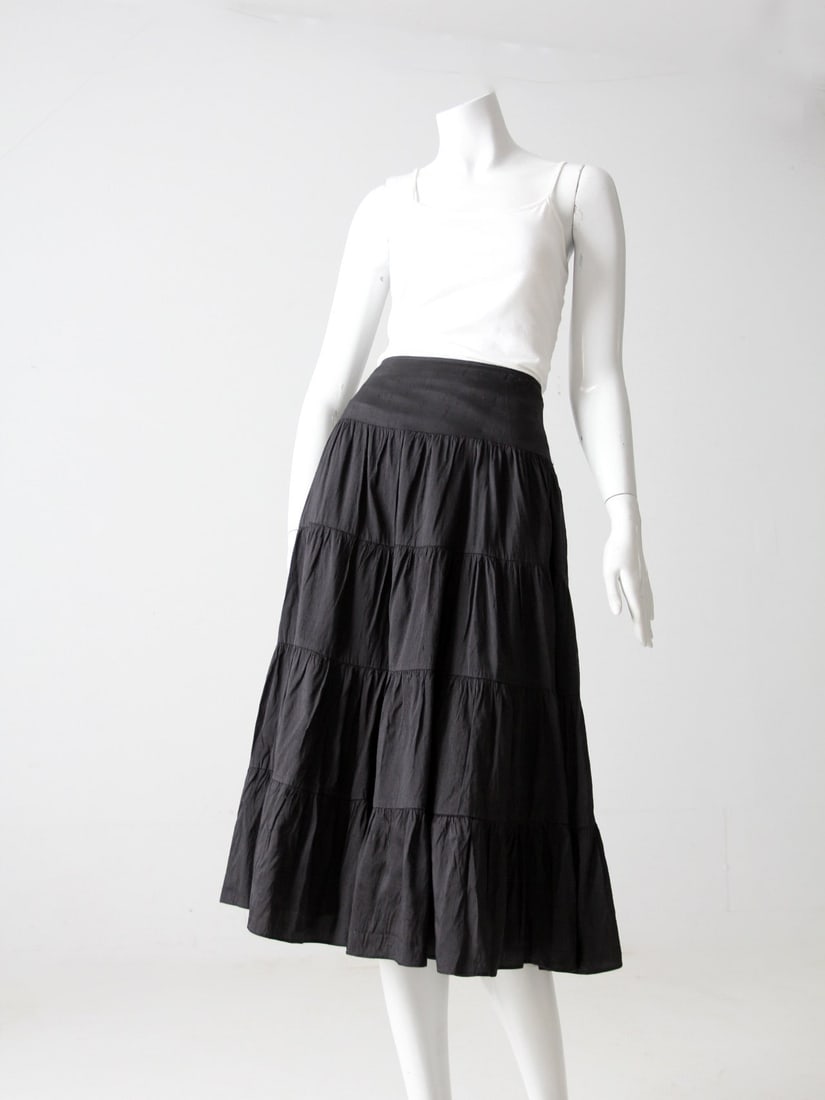 Black Silk Vintage Peasant Skirt with Ruffle Tiered Design: Black Silk Vintage Peasant Skirt with Ruffle Tiered Design This vintage peasant skirt is crafted from 100% black silk, offering a classic prairie style that gracefully falls below the knee. It feature