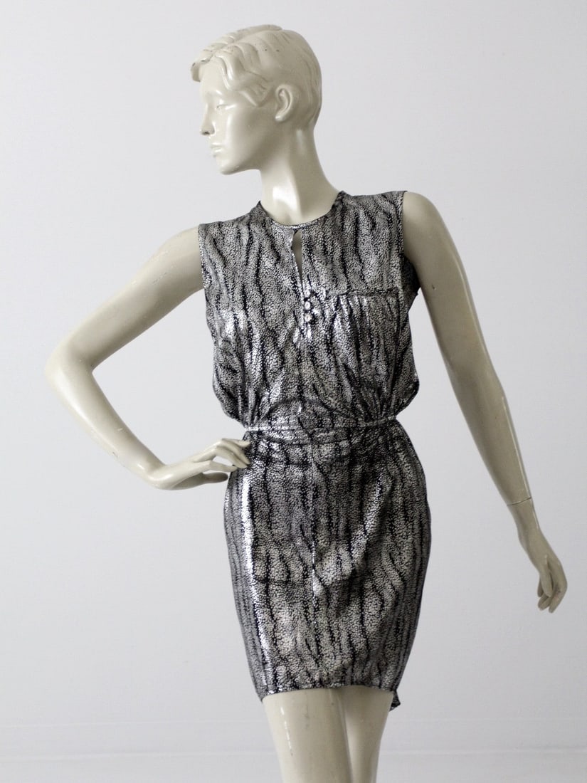 Vintage 80s Metallic Silver and Black Mini Dress with Fishtail Back: Vintage 80s Metallic Silver and Black Mini Dress with Fishtail Back Step back into the vibrant 80s with this stunning vintage metallic mini dress. Crafted in a slinky blend of metallic silver and blac