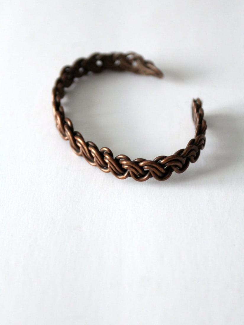 1970s Vintage Copper Cuff Bracelet with Twisted Knot Design: 1970s Vintage Copper Cuff Bracelet with Twisted Knot Design This vintage copper cuff bracelet, dating back to the 1970s, showcases a unique twisted knot chain design that adds a touch of elegance to a