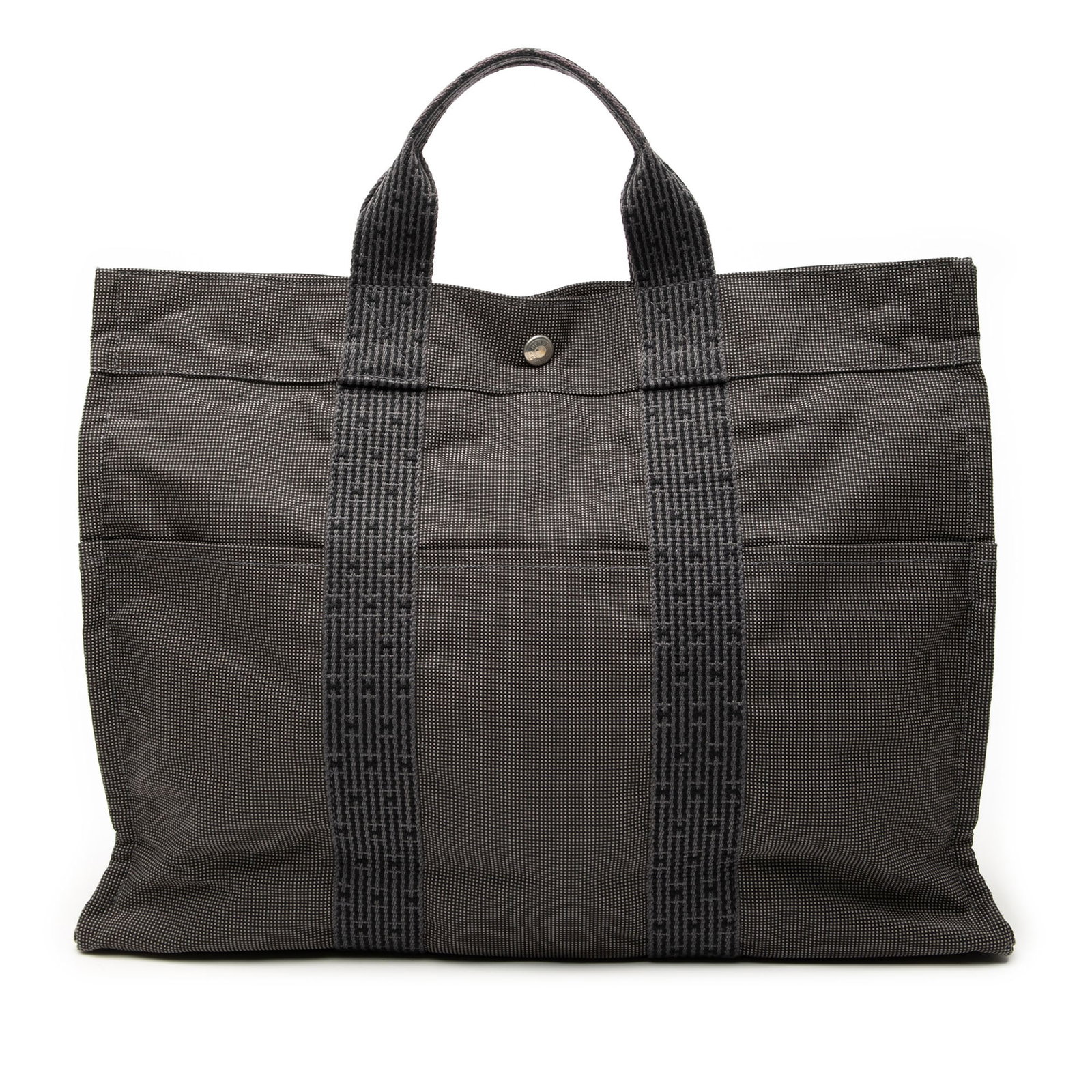 Gray Fabric Tote Herline MM by Hermes with Slip Pockets: Gray Fabric Tote Herline MM by Hermes with Slip Pockets The Hermes Herline Tote MM showcases a canvas body in gray with front and back exterior slip pockets and flat handles. It features a top zip clo