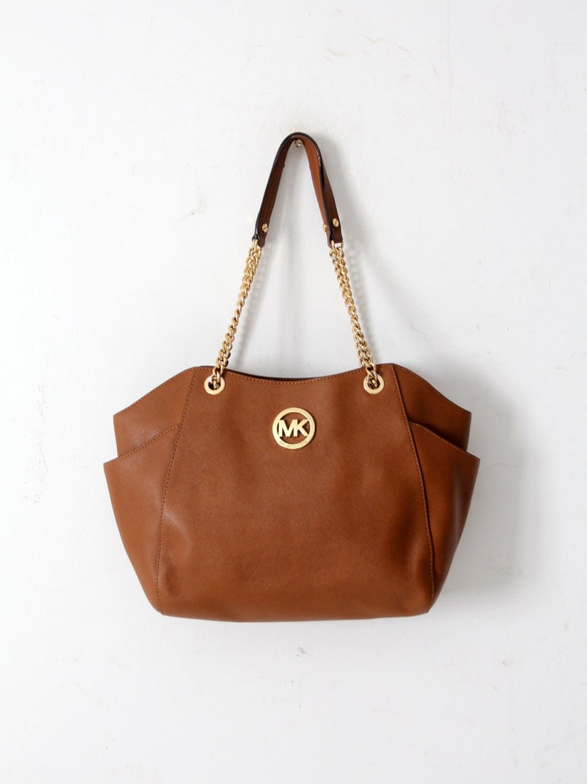 Michael Kors Jet Set Brown Saffiano Leather Tote Bag: Michael Kors Jet Set Brown Saffiano Leather Tote Bag Discover the perfect blend of elegance and functionality with the Michael Kors Jet Set Saffiano Brown Leather Tote Bag. This timeless accessory is 