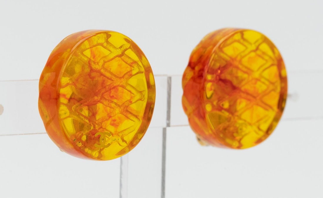 Chanel Lucite Clip On Earrings with Amber Round Cut Stone: Chanel Lucite Clip On Earrings with Amber Round Cut Stone Vintage Chanel clip-on earrings crafted of lucite with a small printed CC logo. The design features amber round-cut stones and was made in Ita