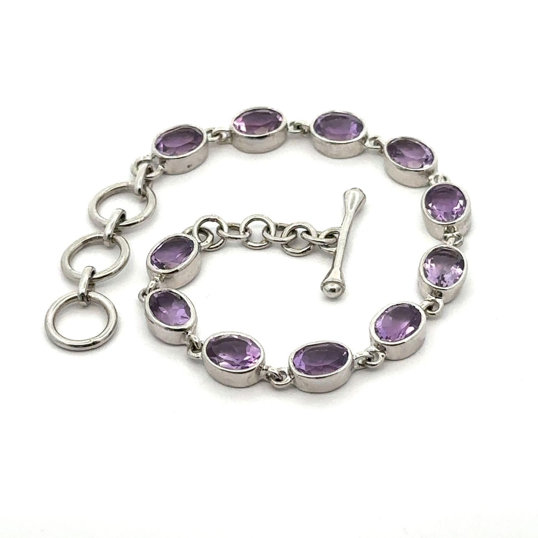 Sterling Silver Adjustable Bracelet with Purple Amethyst Stones: Sterling Silver Adjustable Bracelet with Purple Amethyst Stones This exquisite bracelet features an array of 11 natural genuine amethyst stones, each in an oval brilliant cut, showcasing a beautiful m