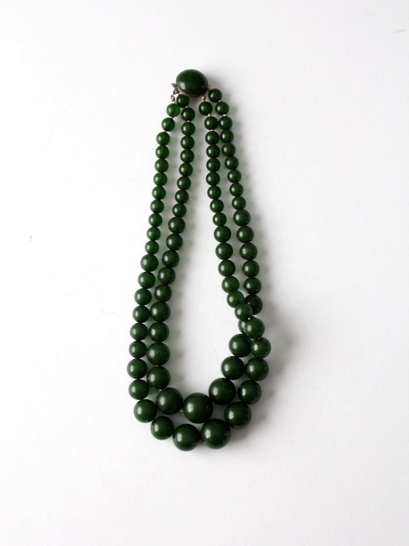 1950s Dark Emerald Bead Double Strand Necklace 15 Inch Tab Clasp: 1950s Dark Emerald Bead Double Strand Necklace 15 Inch Tab Clasp This vintage double strand necklace from the 1950s features dark emerald green spherical beads in graduated sizes. The necklace is secu