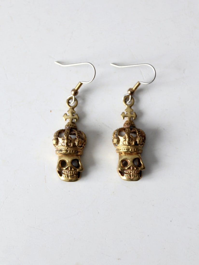 Gold Tone Vintage Skull Dangle Earrings with Crown: Gold Tone Vintage Skull Dangle Earrings with Crown Add a touch of edgy elegance to your style with these Vintage Skull Dangle Earrings. Crafted with a striking gold tone finish, these earrings feature