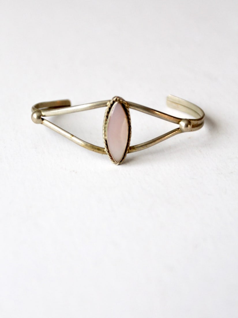 Vintage Silver Tone Cuff Bracelet with Pink Shell Medallion: Vintage Silver Tone Cuff Bracelet with Pink Shell Medallion This vintage cuff bracelet showcases a stylish design featuring slender silver tone metal bands and a beautiful inset pink shell medallion c