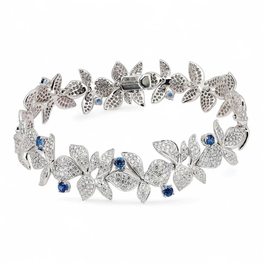 Gubelin 18K White Gold Floral Tennis Bracelet Diamonds Sapphires: Gubelin 18K White Gold Floral Tennis Bracelet Diamonds Sapphires This Gubelin bracelet showcases an elegant floral motif, expertly crafted in 18k white gold. The design features pave-set round brillia