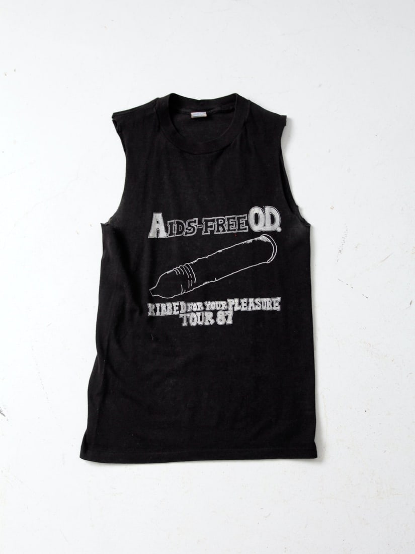1987 Vintage Aids-Free O.D. T-Shirt Black Cotton Blend: 1987 Vintage Aids-Free O.D. T-Shirt Black Cotton Blend This vintage AIDS t-shirt from 1987 is a unique piece of history. Made from a comfortable black cotton blend, it features cut-off sleeves and a c