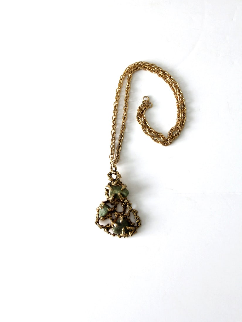 Gold Tone Brutalist Pendant Necklace with Green Stones 21 Inch Chain: Gold Tone Brutalist Pendant Necklace with Green Stones 21 Inch Chain This vintage pendant necklace from the late 1960s to early 1970s showcases a Brutalist design in textured gold tone metal. It featu