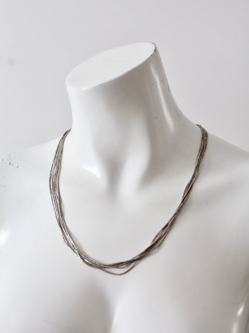 Vintage Liquid Silver Heishi Bead Necklace 21 Inch Five Strands: Vintage Liquid Silver Heishi Bead Necklace 21 Inch Five Strands This vintage "liquid silver" necklace showcases five slinky silver heshi beaded strands, elegantly arranged for a timeless appeal. The n