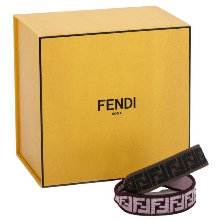 Fendi Set of 2 Monogram Strap Bracelets with Gold Hardware: Fendi Set of 2 Monogram Strap Bracelets with Gold Hardware This elegant set of two Fendi Monogram strap bracelets showcases a stylish blend of pink, brown, and black colors, making them a versatile ac