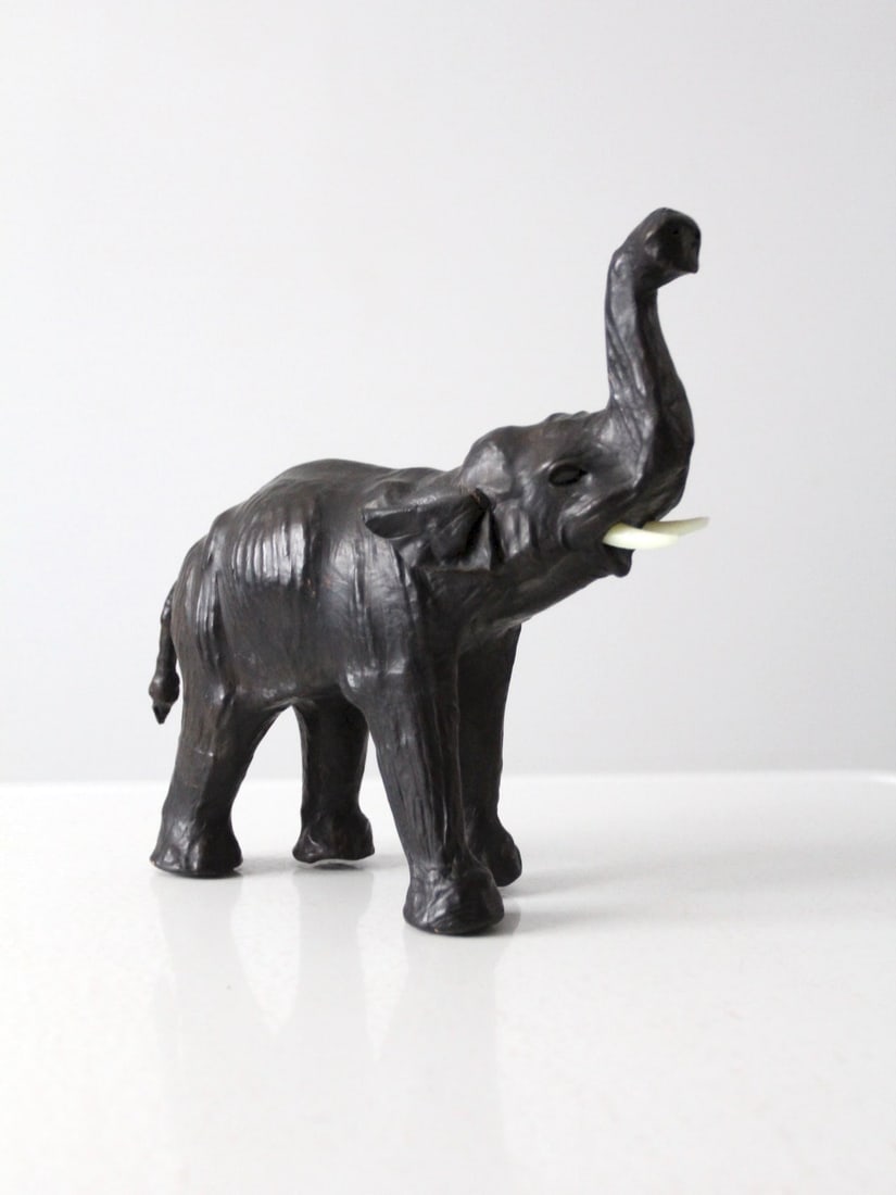 Handcrafted Vintage Leather Elephant Sculpture with Glass Eyes: Handcrafted Vintage Leather Elephant Sculpture with Glass Eyes This vintage leather elephant sculpture is a hand-crafted masterpiece made from aged black leather, featuring detailed glass eyes. The le