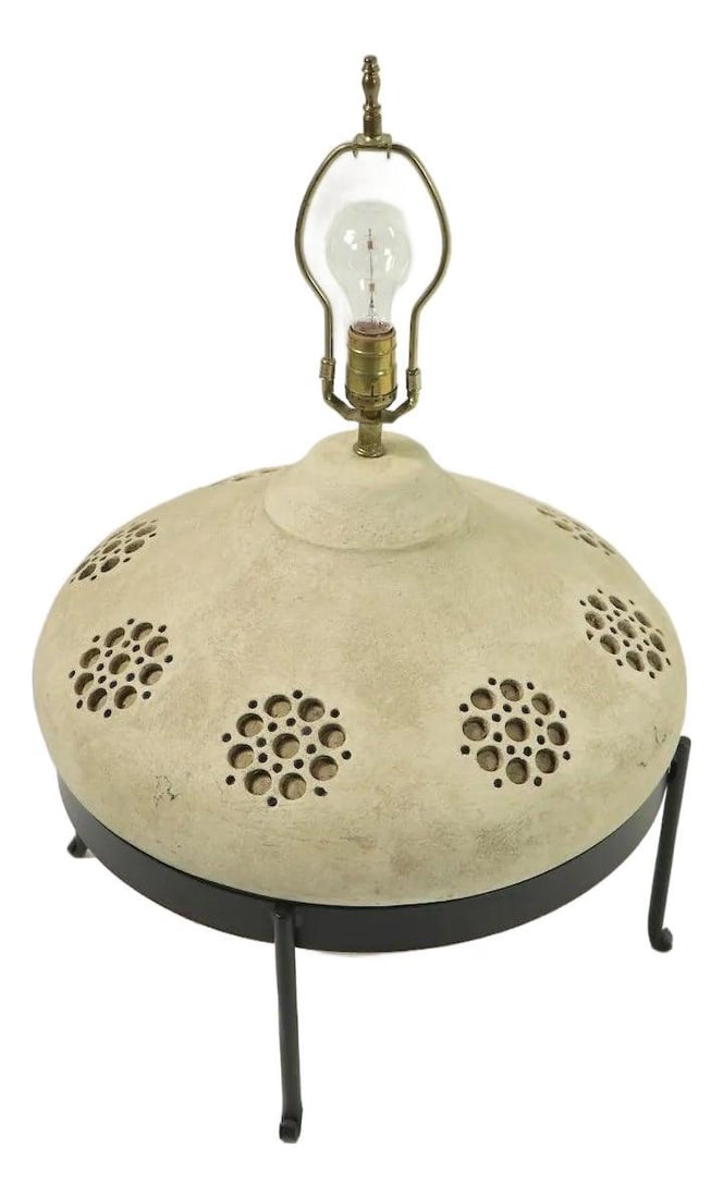 1970s Ceramic Lamp with Wrought Iron Base and Circular Cutout Design: 1970s Ceramic Lamp with Wrought Iron Base and Circular Cutout Design This 1970s ceramic table lamp features a sand-colored, large bulbous base with circular cut-away decorative elements, set in its or