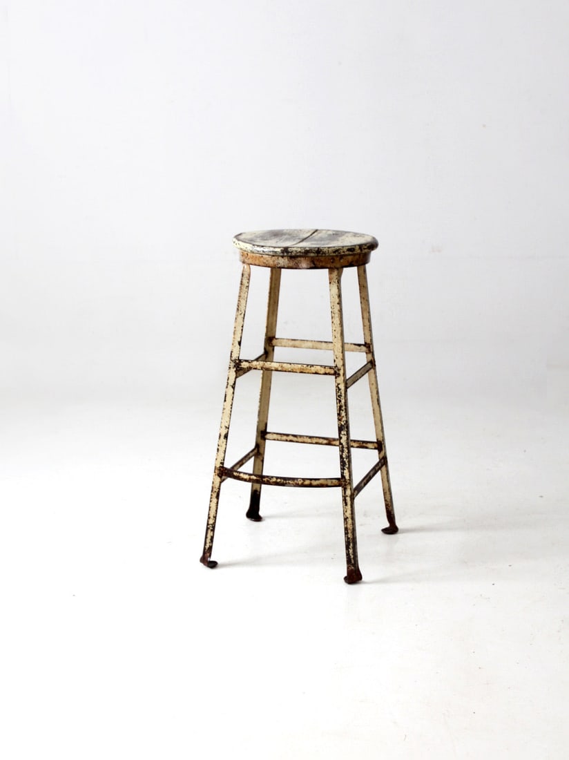Vintage Industrial Metal Stool Butter Yellow Wood Seat: Vintage Industrial Metal Stool Butter Yellow Wood Seat This vintage industrial stool combines a sturdy metal frame with a beautifully aged wooden seat, showcasing a rustic charm. The bar-height design