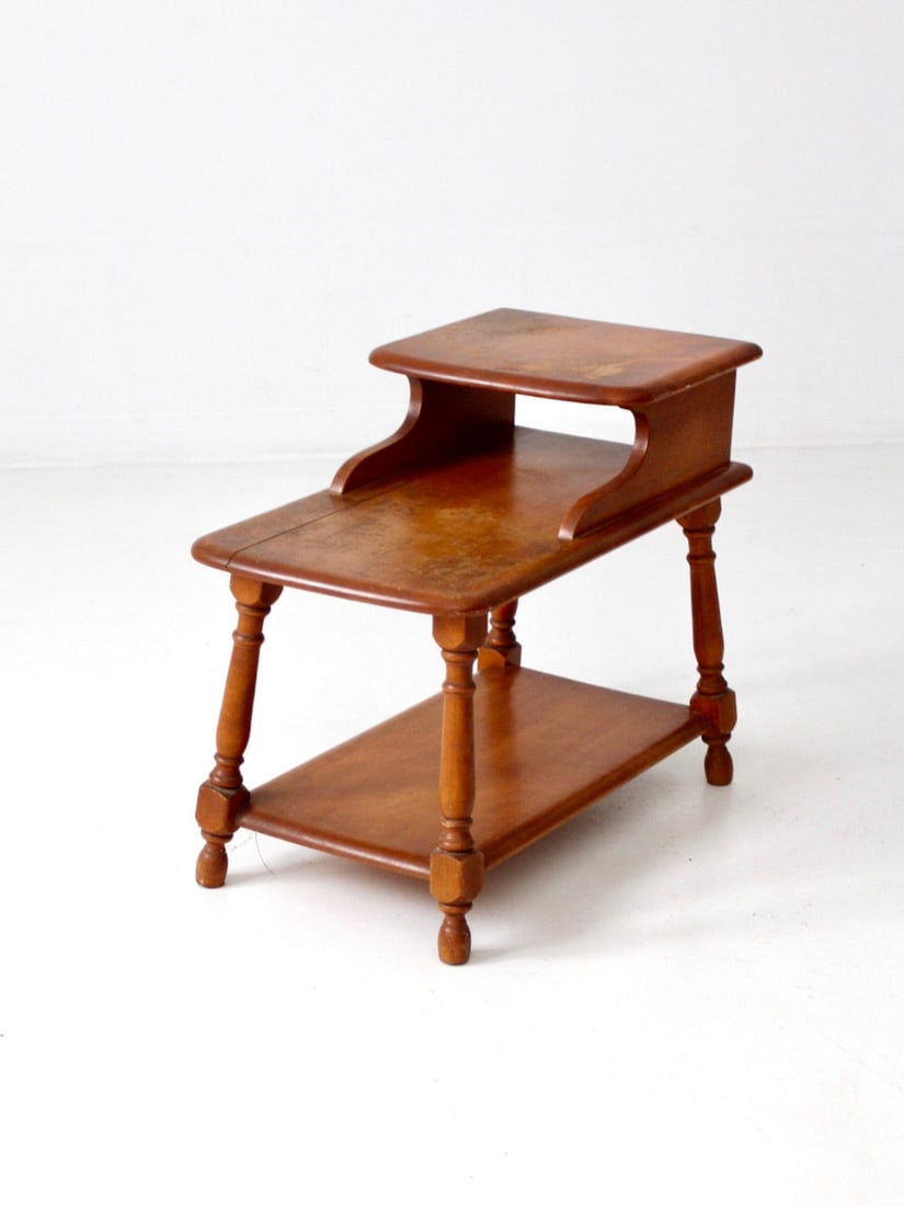Colonial Revival Tiered Wood End Table with Lower Shelf: Colonial Revival Tiered Wood End Table with Lower Shelf Mid-Century Colonial Revival step end table with a tiered wood form, turned legs, curved side supports, and a lower shelf. The aged surface and 