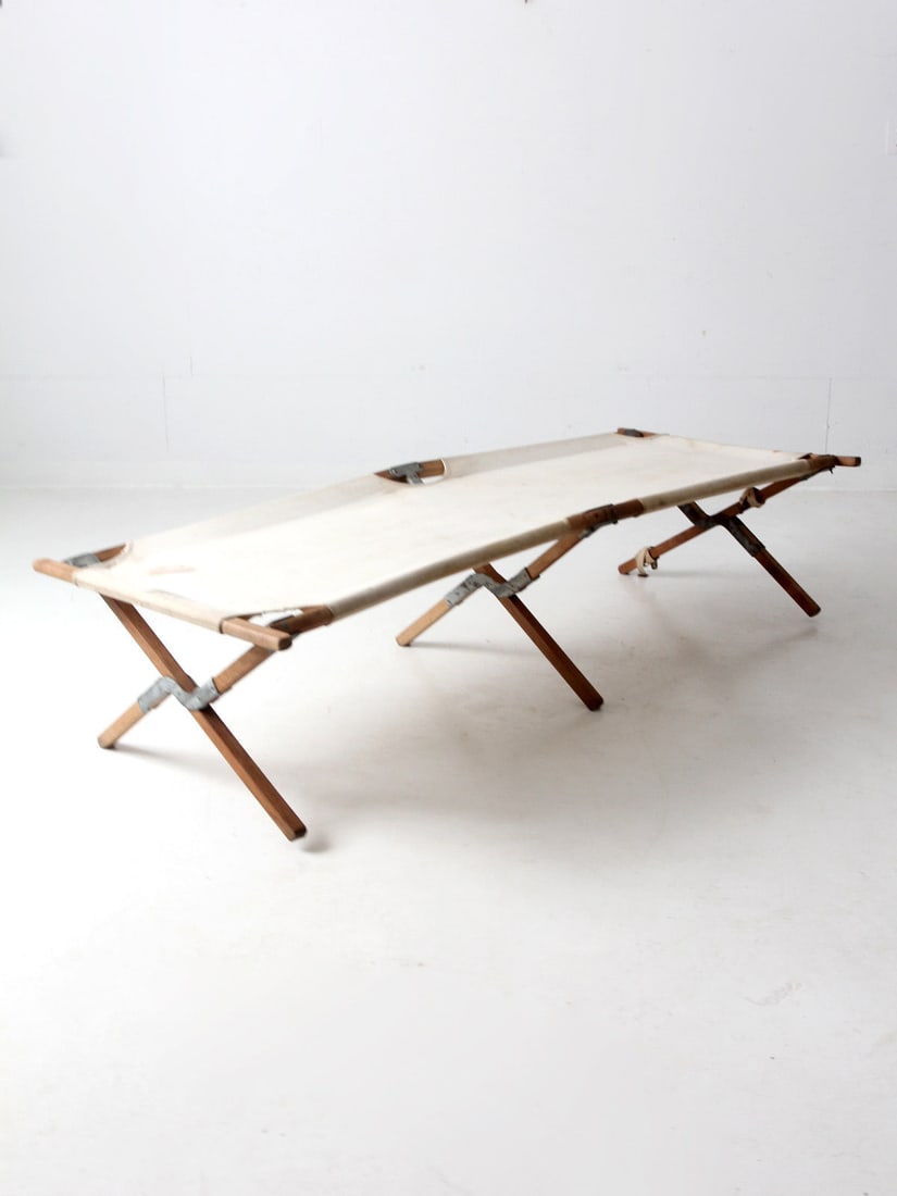 Vintage 1930s-1950s Wood Canvas X-Frame Folding Cot: Vintage 1930s-1950s Wood Canvas X-Frame Folding Cot This vintage X-frame cot, dating from the 1930s to 1950s, showcases a classic design with a sturdy wood frame and cream-colored canvas top. The cot 