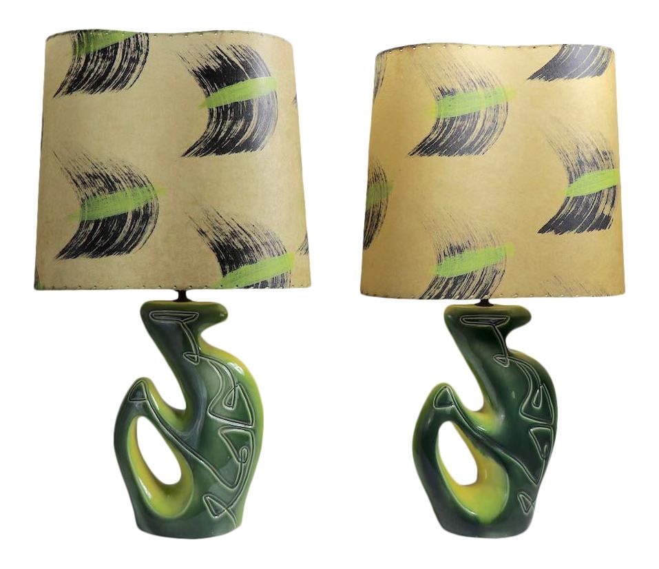 Pair of Mid Century Green Ceramic Table Lamps with Original Shades: Pair of Mid Century Green Ceramic Table Lamps with Original Shades This stunning pair of Mid Century table lamps features a unique organic form with green ceramic bases that showcase intricate incised