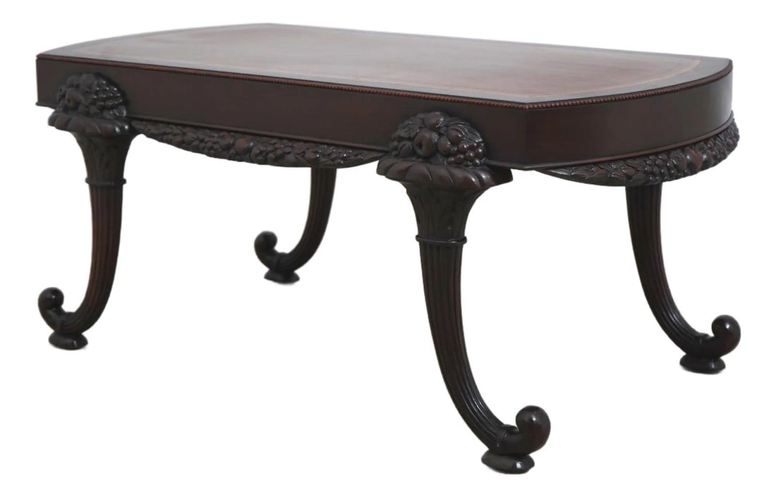 1940s Mahogany Coffee Table with Leather Top Cornucopia Carving: 1940s Mahogany Coffee Table with Leather Top Cornucopia Carving This vintage coffee table from the 1940s features a Greek key embossed leather top and is crafted from mahogany. The table showcases fin
