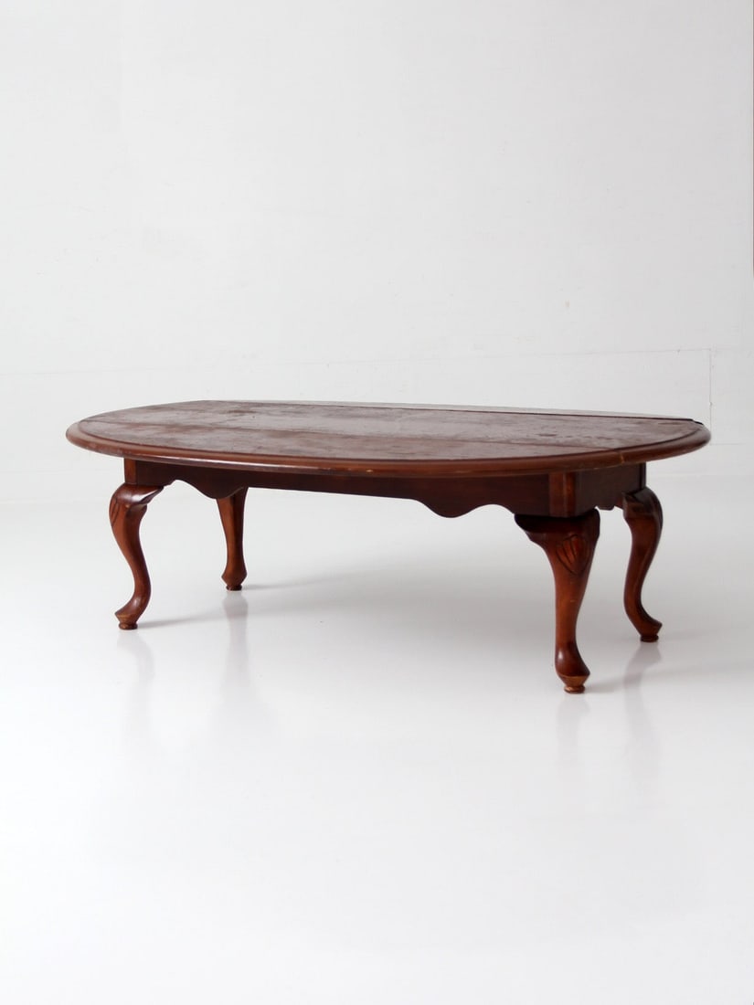 Queen Anne drop leaf coffee table with cabriole legs: Queen Anne drop leaf coffee table with cabriole legs This mid-20th century Queen Anne drop leaf coffee table features an elongated oval shape with carved shell accents and gracefully curved cabriole l