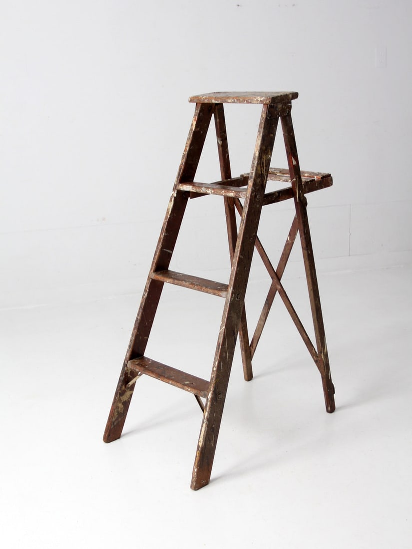 Vintage Brown Wood A Frame Step Ladder with Fold Out Shelf: Vintage Brown Wood A Frame Step Ladder with Fold Out Shelf This vintage wooden A-frame folding ladder features a classic brown finish with unique paint splatters and drips in multiple colors, reflecti