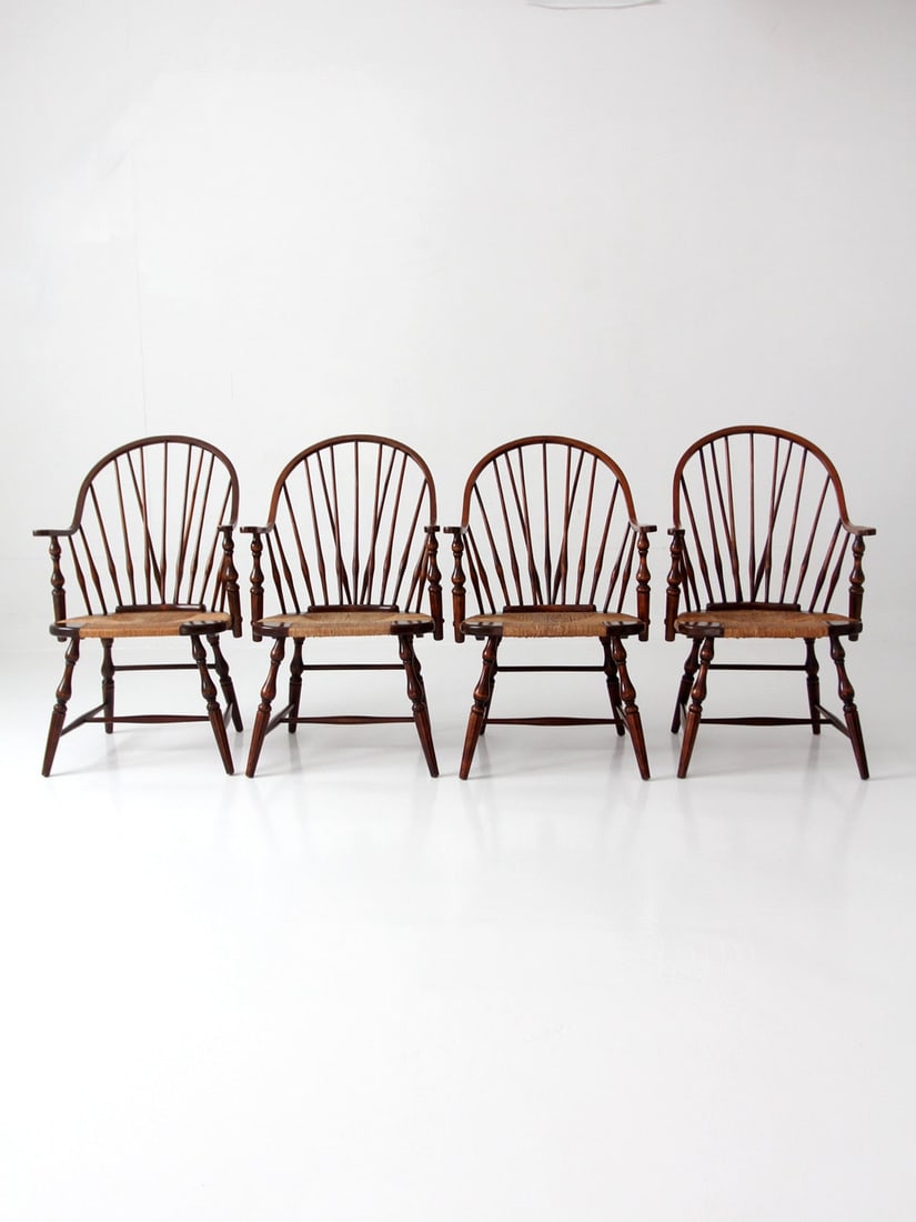 Set of Four Sack Back Windsor Armchairs With Rush Seats: Set of Four Sack Back Windsor Armchairs With Rush Seats This set of four vintage Windsor armchairs features a classic sack-back silhouette with tall, radiating spindles. The curved crest rail and shap