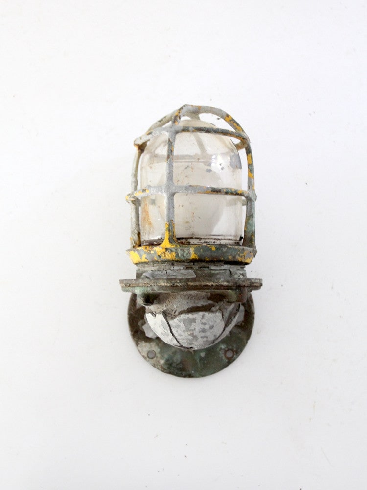 Vintage R & S Co Ship Sconce Light with Metal Cage: Vintage R & S Co Ship Sconce Light with Metal Cage This vintage ship sconce light from R & S Co. showcases a unique design with a metal cage surrounding the bulb, complemented by a round back for easy