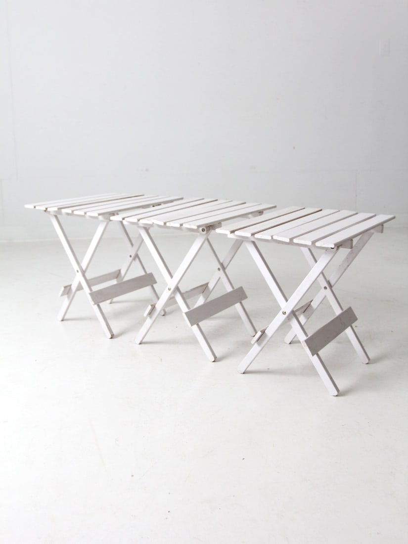 Set of 3 Vintage White Slat Wood Folding End Tables: Set of 3 Vintage White Slat Wood Folding End Tables This set of three vintage end tables from the mid 20th century features a classic design with painted white folding frames and slat wood table tops.