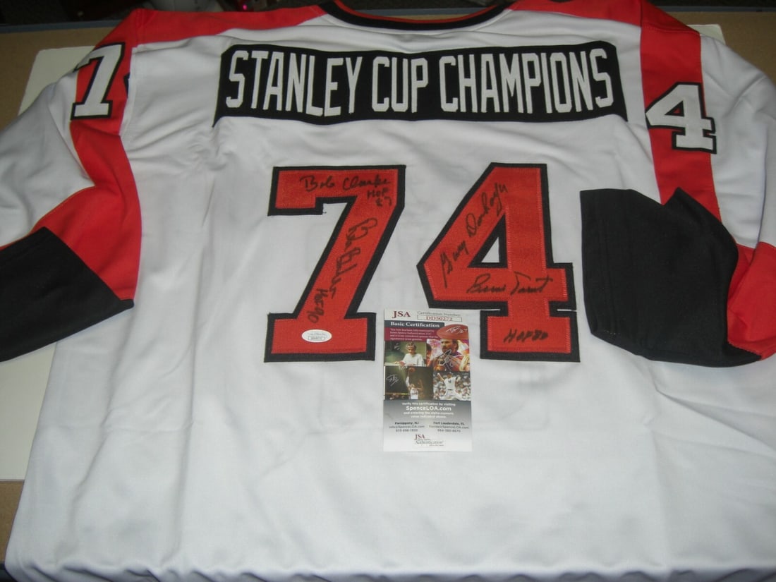Signed 1974 Stanley Cup Champions Jersey JSA COA Clarke Barber Parent Dorn: Signed 1974 Stanley Cup Champions Jersey JSA COA Clarke Barber Parent Dorn This is a pre-owned hockey jersey signed by Bob Clarke, Bill Barber, Bernie Parent, and Gary Dornhoefer, commemorating the 19