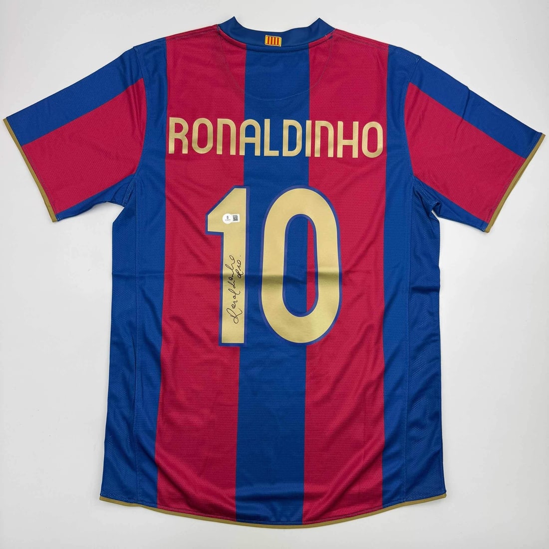 Ronaldinho Autographed FC Barcelona Jersey Beckett Authenticated: Ronaldinho Autographed FC Barcelona Jersey Beckett Authenticated This is an autographed soccer jersey featuring Ronaldinho, the legendary player from FC Barcelona. The jersey is custom-made in blue an