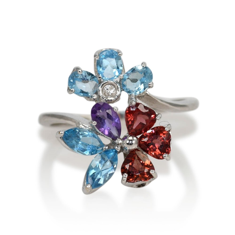 Floral Blue Topaz Garnet Amethyst Diamond Ring in 18K White Gold: Floral Blue Topaz Garnet Amethyst Diamond Ring in 18K White Gold Pre-owned ladies floral design ring set with blue topaz, garnet, amethyst, and a small diamond in 18k white gold. The ring is stamped 7