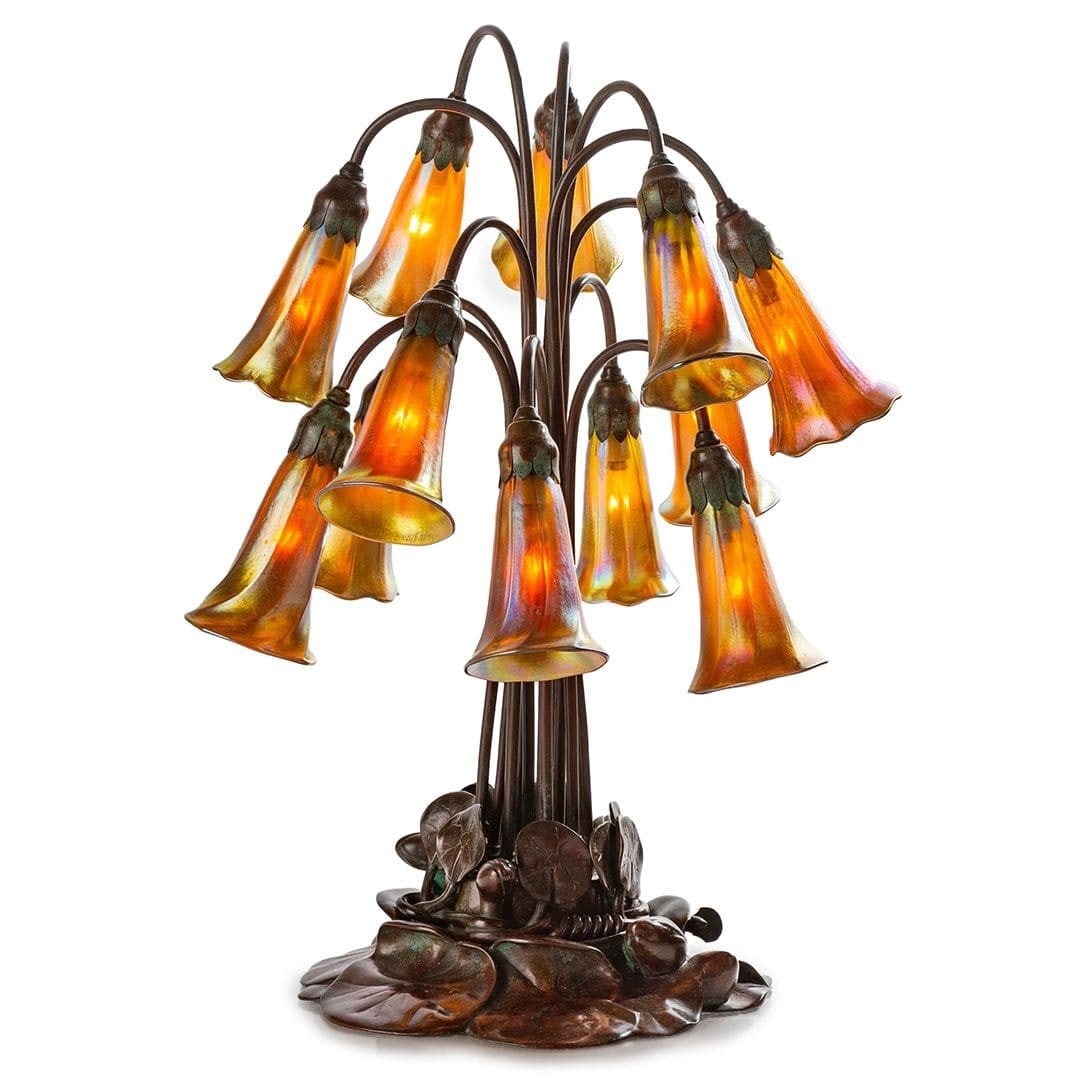 Tiffany Studios 12 Light Lily Table Lamp Antique Bronze: Tiffany Studios 12 Light Lily Table Lamp Antique Bronze This antique table lamp, crafted by Tiffany Studios around 1905, features twelve Favrile glass lily shades, each signed "L.C.T. Favrile." The la