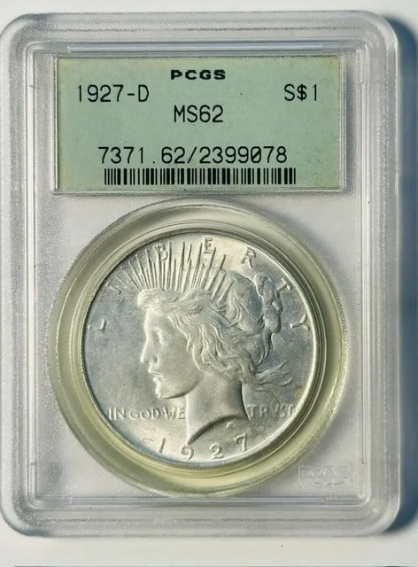 PCGS MS-62 1927-D Peace Silver Dollar in Old Green Holder: PCGS MS-62 1927-D Peace Silver Dollar in Old Green Holder 1927-D Peace Dollar certified by PCGS and graded MS-62, housed in an OGH (Old Green Holder). This pre-owned silver dollar is a USA issue with 