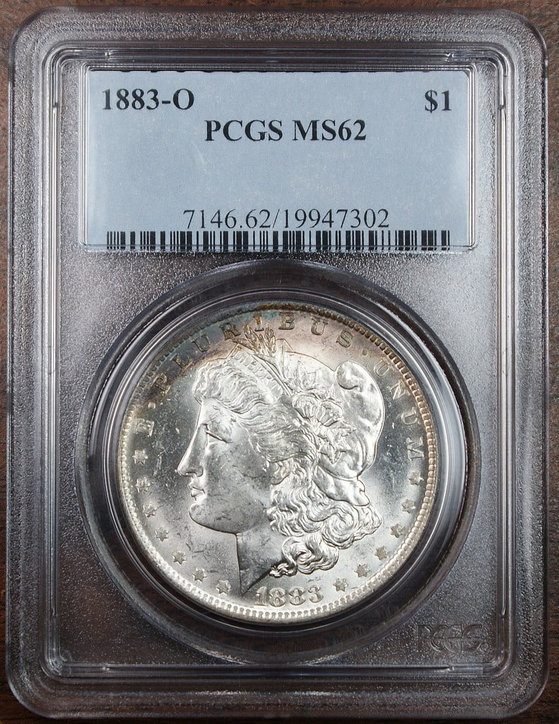 PCGS MS-62 1883-O Morgan Dollar Silver Coin With Colorful Peripheral Toning: PCGS MS-62 1883-O Morgan Dollar Silver Coin With Colorful Peripheral Toning This 1883-O Morgan Silver Dollar is graded MS-62 by PCGS and features vibrant peripheral toning along the edge. Struck at th