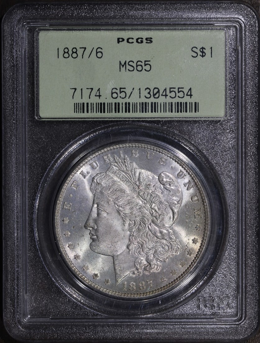 PCGS MS65 1887 6 Morgan Silver Dollar OGH Overdate: PCGS MS65 1887 6 Morgan Silver Dollar OGH Overdate This is an 1887/6 Morgan Silver Dollar graded MS65 by PCGS, featuring the notable overdate variety. The coin is uncirculated and composed of 0.9 fine