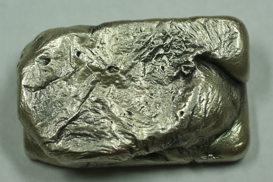 4.9 Troy Ounce .999 Fine Silver Poured Bar Unbranded: 4.9 Troy Ounce .999 Fine Silver Poured Bar Unbranded This is an unbranded silver poured bar weighing 4.9 troy ounces, composed of .999 fine silver. The bar features a rough, textured surface and is of