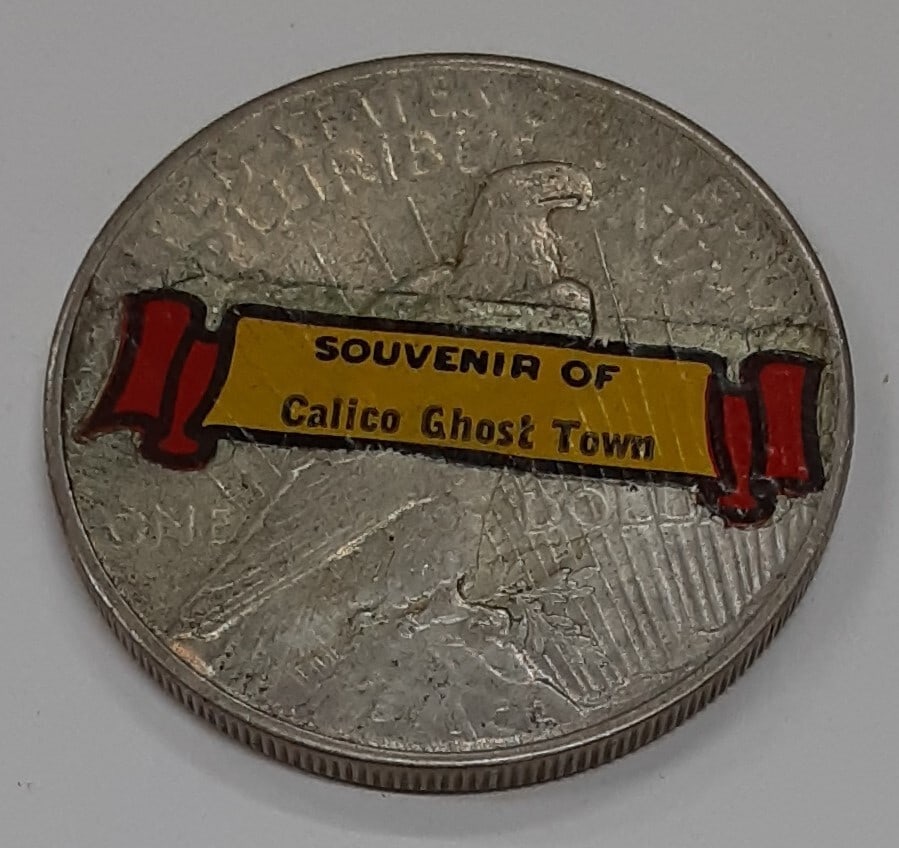1925 Peace Dollar Silver Coin Calico Ghost Town Souvenir Stickered Reverse: 1925 Peace Dollar Silver Coin Calico Ghost Town Souvenir Stickered Reverse This 1925 Peace Silver Dollar features a sticker on the reverse, serving as a souvenir from Calico Ghost Town in California. 